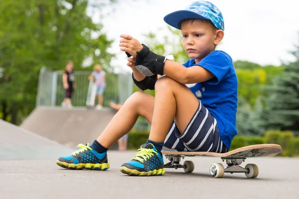 Kleine jongen elleboog pads op de Skatepark zetten — Stockfoto