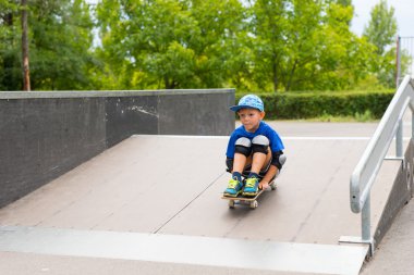 Oturan çocuk kaykay ve rampa sürme