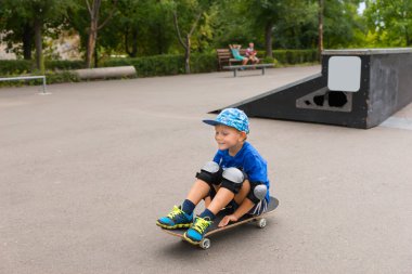 Skate Park kaykay üzerinde oturan Boy gülümseyerek