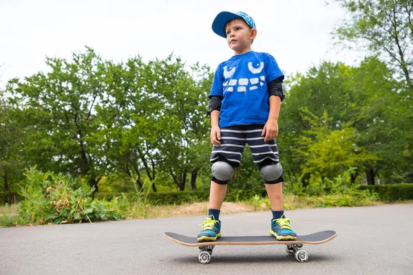 Serious Boy Standing on Skateboard in Paved Lot — Stock Photo, Image