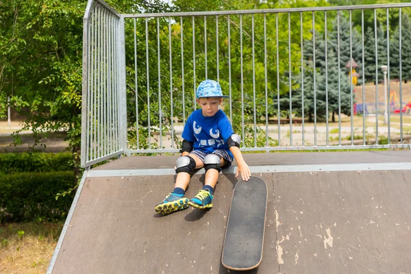 Мальчик катается на скейтборде вниз по рампе в скейт-парке — стоковое фото
