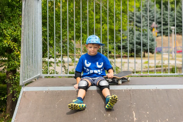 Νεαρό αγόρι με Skateboard που κάθεται στην κορυφή του κεκλιμένου επιπέδου — Φωτογραφία Αρχείου