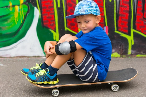 Мальчик сидит на скейтборде в скейт-парке — стоковое фото