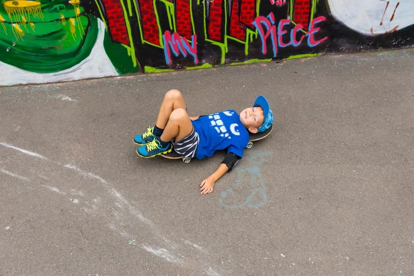 Мальчик лежит на скейтборде в скейт-парке — стоковое фото