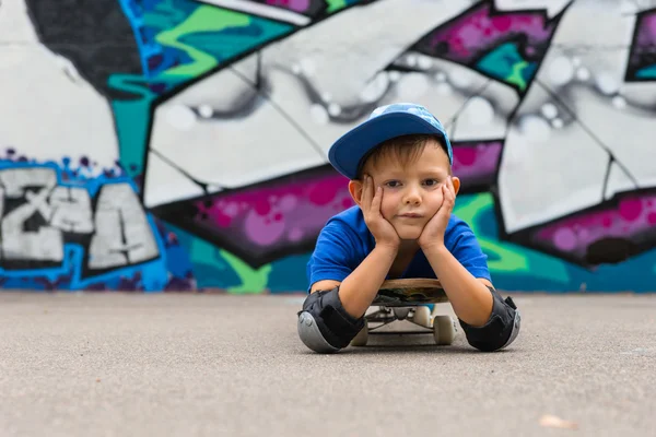 Ragazzo sdraiato sullo skateboard con poggiatesta in mano — Foto Stock