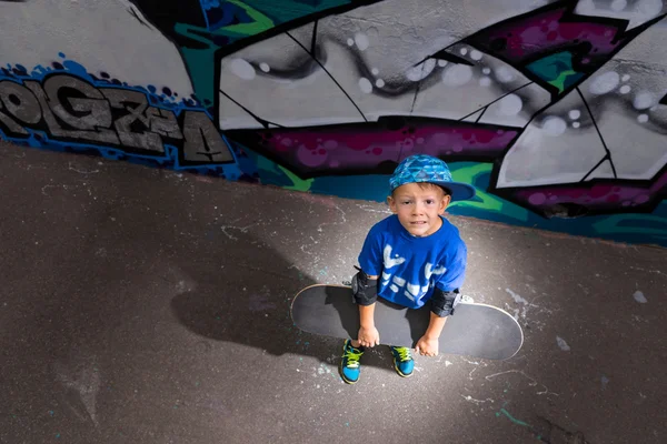 Menino com skate dramaticamente lit no parque de skate — Fotografia de Stock