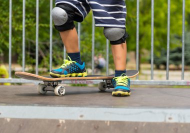 Boy with One Foot on Skateboard on Top of Ramp