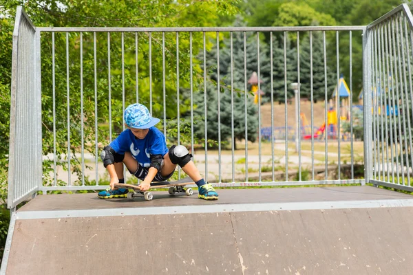 Giovane ragazzo seduto su skateboard in cima alla rampa — Foto Stock