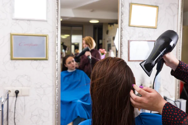 Cabelo de secagem estilista do cliente feminino no salão — Fotografia de Stock