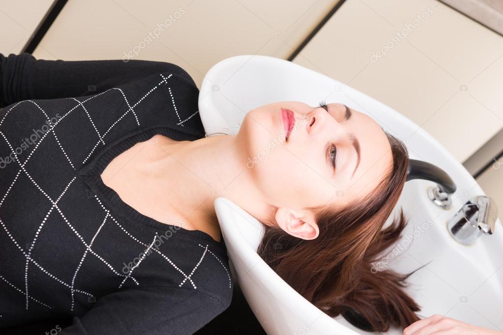 Brunette Woman Lying Back with Head in Salon Sink