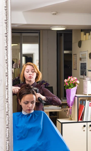 Reflexão do cabelo de secagem estilista do cliente — Fotografia de Stock
