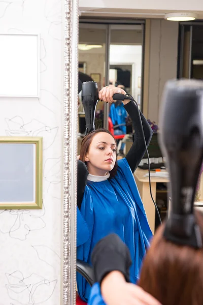 Reflexão da mulher no cabelo de secagem de sopro de salão — Fotografia de Stock