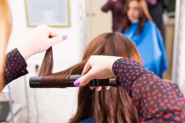 Estilista usando ferro liso para estilo clientes cabelo — Fotografia de Stock