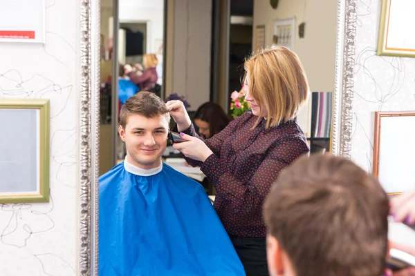 Jovem homem tendo cabelo cortado por salão estilista — Fotografia de Stock