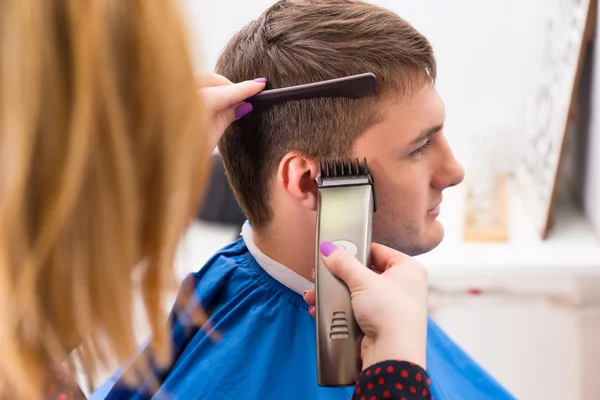 Estilista usando maquinilla de afeitar para cortar el cabello del cliente masculino —  Fotos de Stock