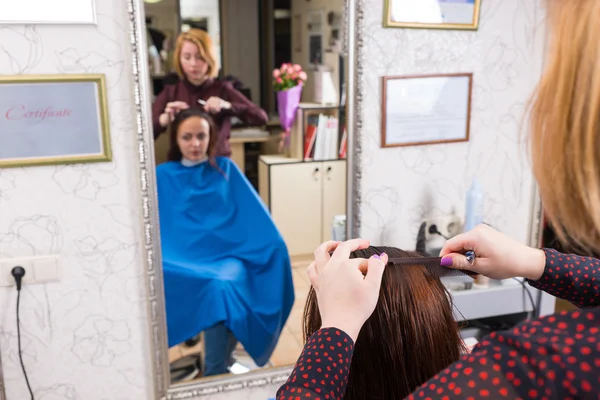 Refleksjon av Stylist Combing Hair of Client – stockfoto