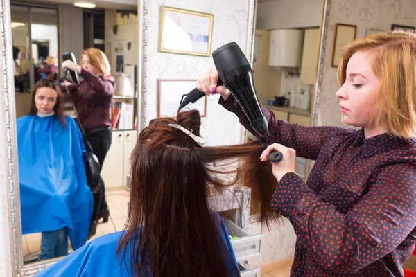 Estilista Blow Secado de cabello de cliente en el salón —  Fotos de Stock