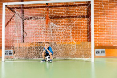 Bir kapalı futbol sahada bekleyen sıkılmış genç çocuk