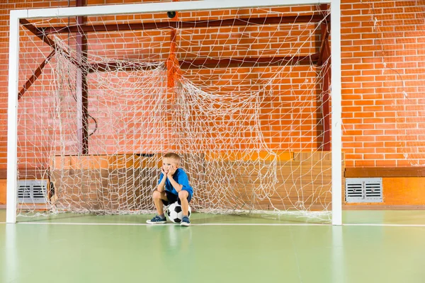 Uttråkad ung pojke väntar på en inomhus fotboll domstol — Stockfoto