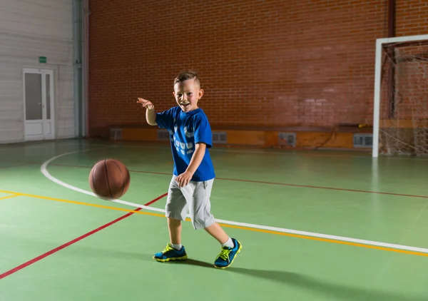 Skrattande ung pojke spela basket — Stockfoto