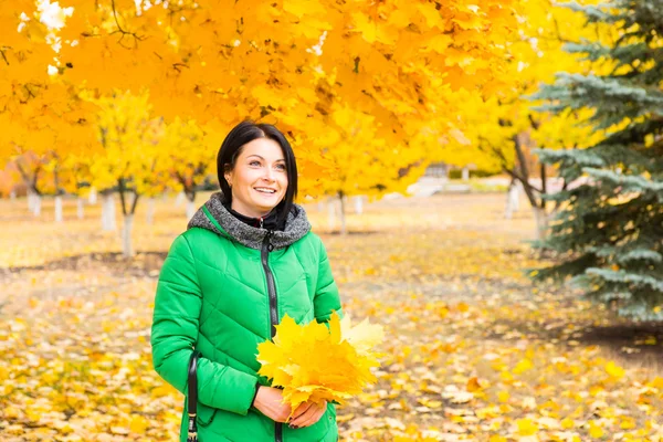 Glückliche junge Frau sammelt gelbe Herbstblätter — Stockfoto