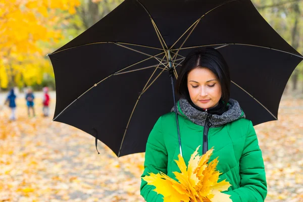 Mooie jonge vrouw met een handvol gele bladeren — Stockfoto