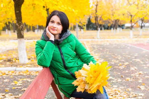 Mujer joven pensativa relajándose en un banco de otoño — Foto de Stock