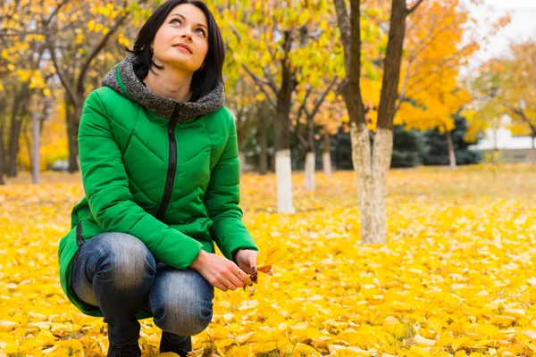 Jonge vrouw genieten van heldere gele herfst bladeren — Stockfoto