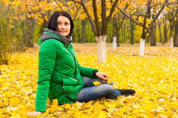 Atractiva mujer relajándose entre las hojas de otoño — Foto de Stock