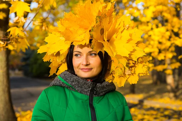 Mujer joven sonriente con un sombrero de hojas de otoño — Foto de Stock