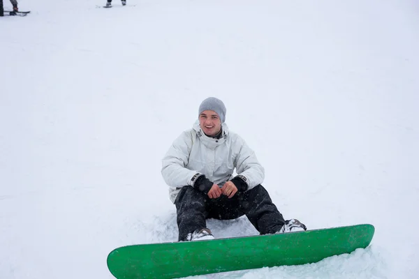 Giovane uomo fuori snowboard seduto nella neve — Foto Stock