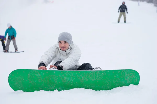 Guapo chico apretando su snowboard en la nieve —  Fotos de Stock