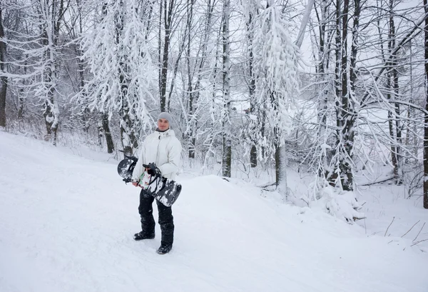 Молодой человек несет свой сноуборд в гору — стоковое фото