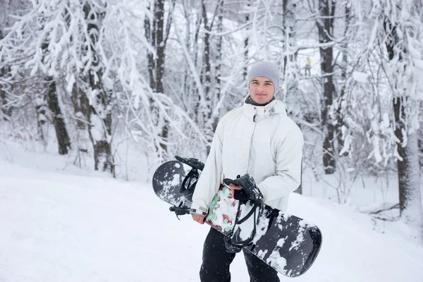 Sorridente bel giovane uomo con uno snowboard — Foto Stock