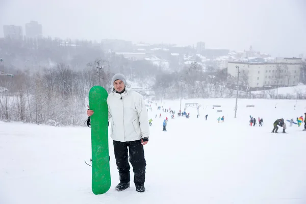 Joven con un colorido snowboard verde —  Fotos de Stock