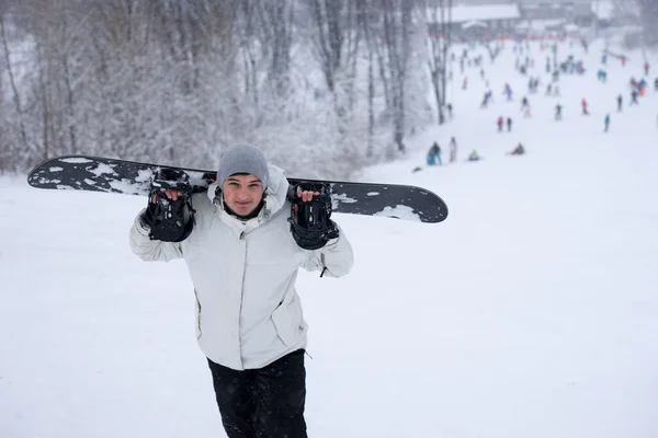 Giovane snowboarder portando la sua tavola — Foto Stock