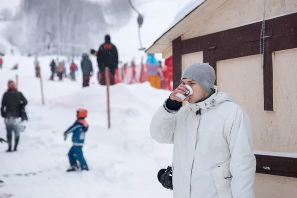 年轻男子站在一个滑雪胜地的喝咖啡 — 图库照片