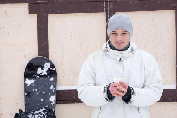 Snowboarder taking a break with hot coffee — Stockfoto