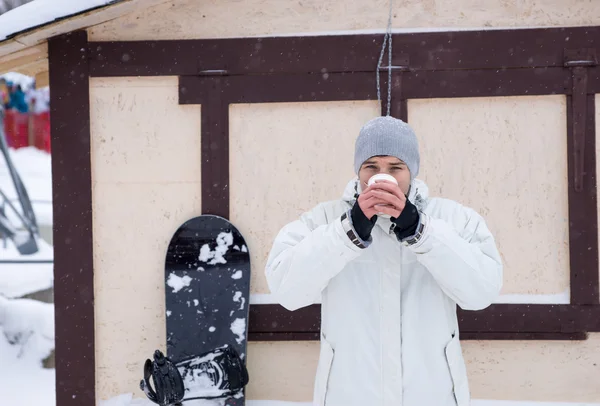 Сноубордист пьет из чашки на горнолыжном курорте — стоковое фото