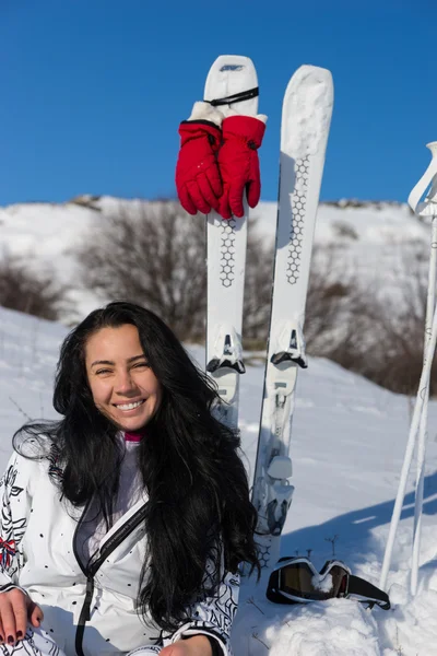 Esquiadora sentada en la colina nevada con esquís —  Fotos de Stock