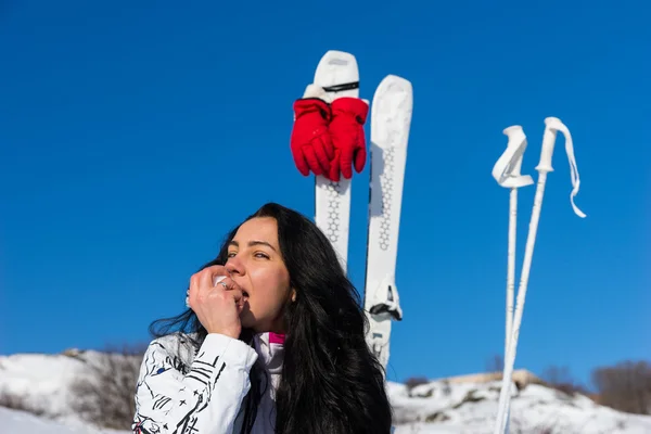 Mujer joven con esquís comiendo una manzana en Hillside — Foto de Stock