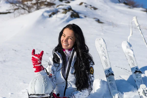 Vrouwelijke skiër zittend op heuvel handgebaar maken — Stockfoto