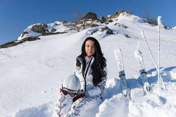 Лыжница, сидящая на снежном склоне с лыжами — стоковое фото