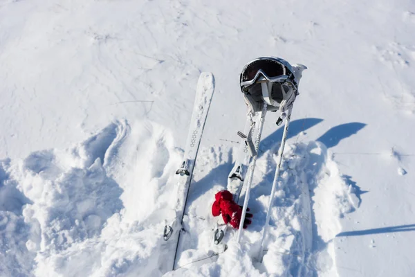 Hjälm, skyddsglasögon, stavar och skidor på snöiga sluttning — Stockfoto