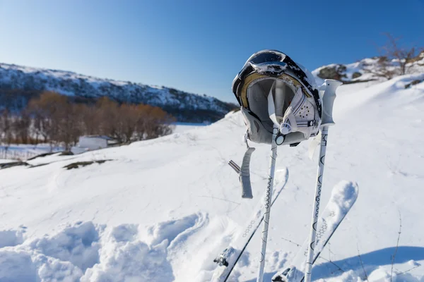 Casco, gafas postes y esquís en la montaña nevada — Foto de Stock