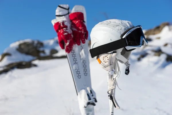 头盔和护目镜与滑雪板和山上的两极 — 图库照片