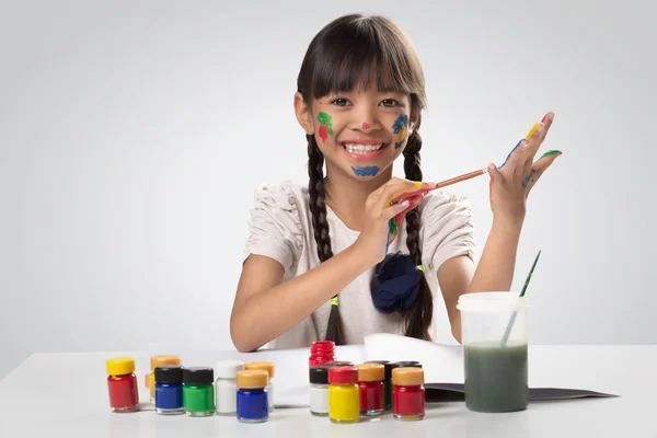 Little asian girl with her hands in the paint — Stock Photo, Image