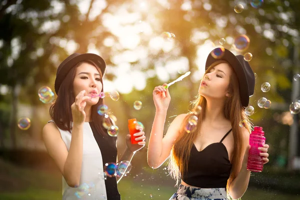 Beautiful asian teen girls blowing soap bubbles — Stock Photo, Image