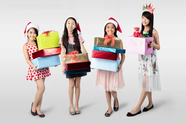 Quatro jovens meninas asiáticas com chapéu vermelho segurando presentes — Fotografia de Stock