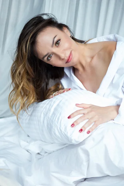 Chica en la cama abrazando una almohada — Foto de Stock